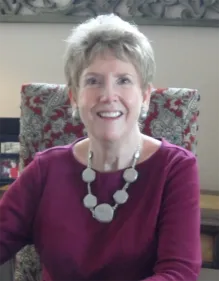 A woman sitting in a chair wearing a necklace.