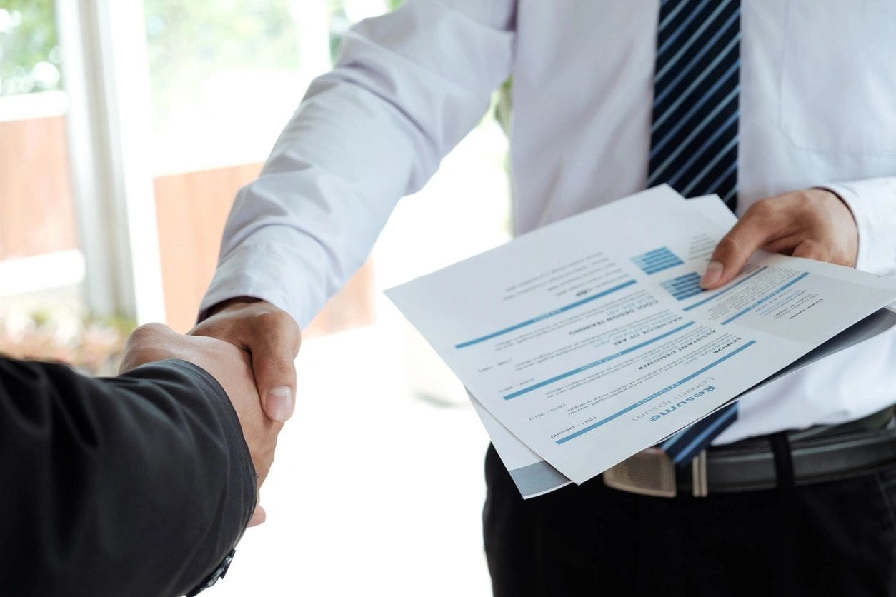 Two people shaking hands over a document.