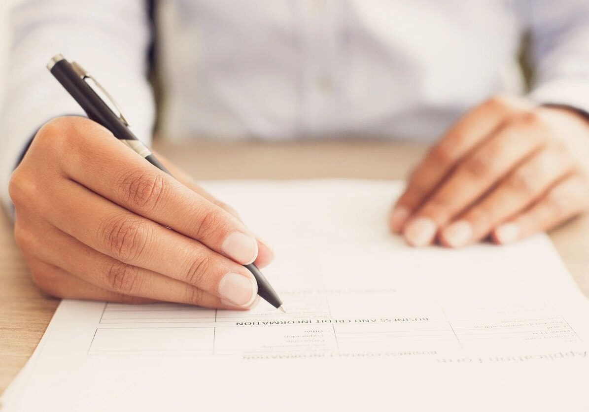 A person writing on paper with a pen.